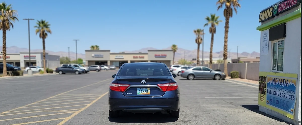 Henderson driver pulling away from a Smog Busters hut with fresh Nevada plate stickers visible on the rear bumper